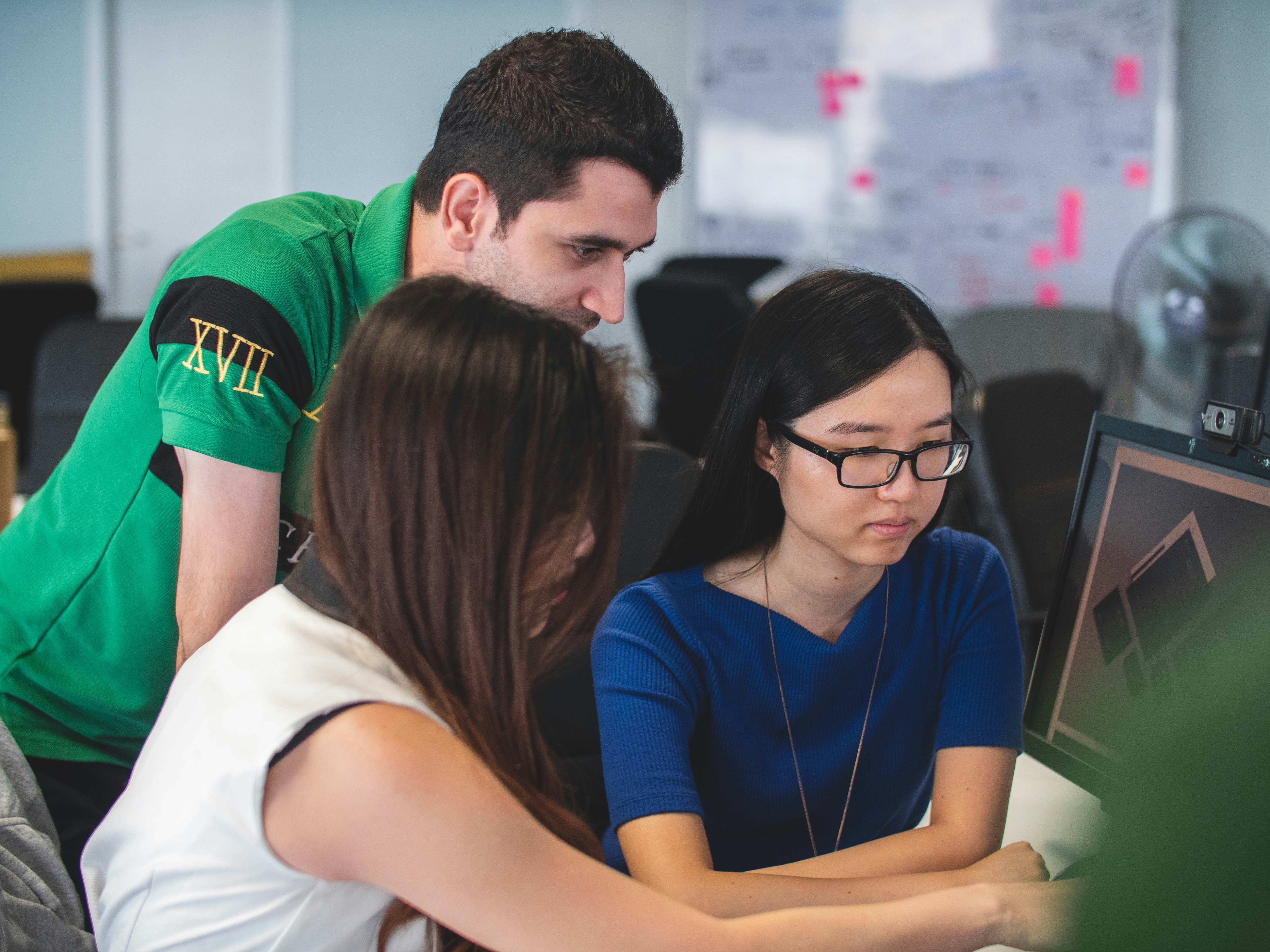 Team collaborating and helping at computers